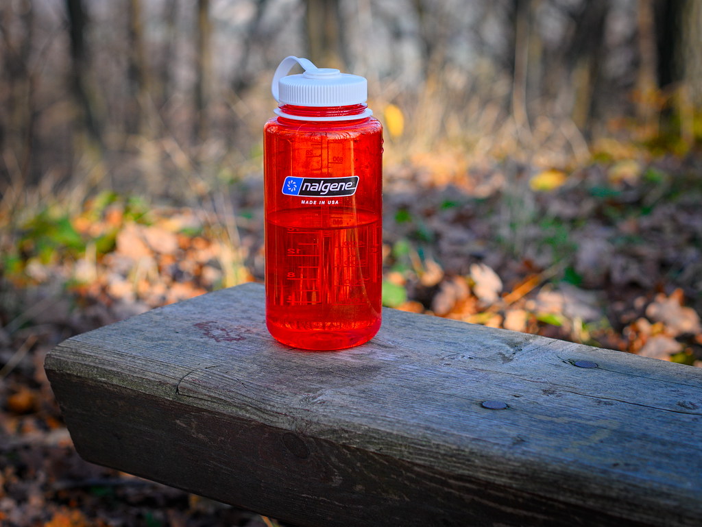 red reusable water bottle in the forest