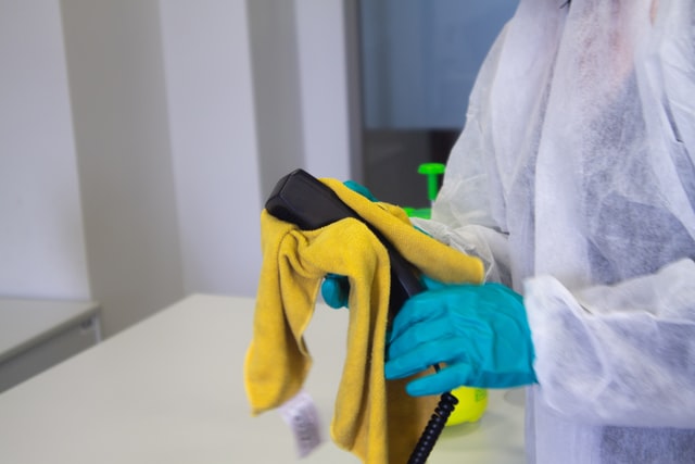 a professional cleaner sanitizing a phone
