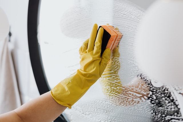 cleaning a mirror with a sponge and a soapy solution