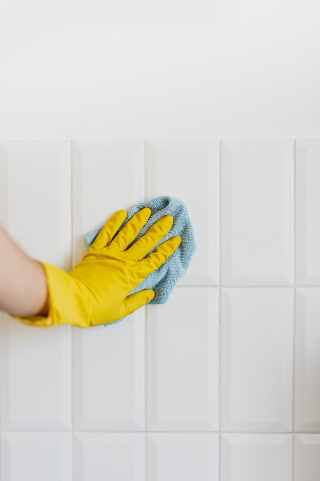 a microfiber cloth being used to clean a white tile wall