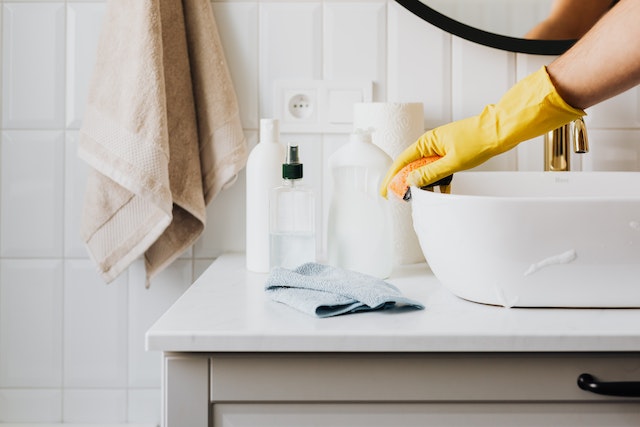 a white bathroom sink being cleaned by a home cleaner