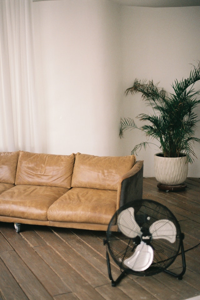 a brown couch and small house fan