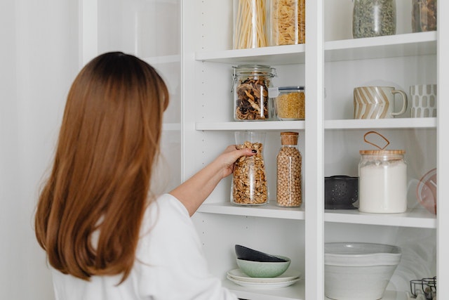 a women grabbing a container of dried food off a shelf